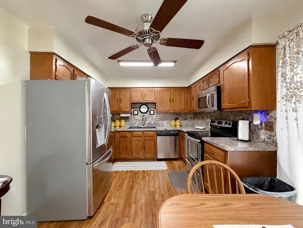 a kitchen with stainless steel appliances granite countertop a refrigerator a sink dishwasher a stove with wooden cabinets and floor