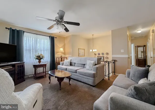 a living room with furniture a ceiling fan and a flat screen tv