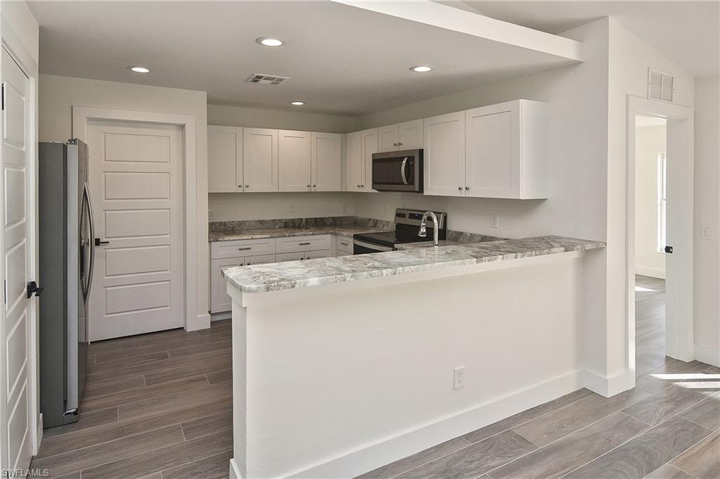 785 Homestead Road South Lehigh Acres, FL 33974 - Photo 23 of 49 a kitchen with stainless steel appliances granite countertop a sink stove refrigerator and cabinets
