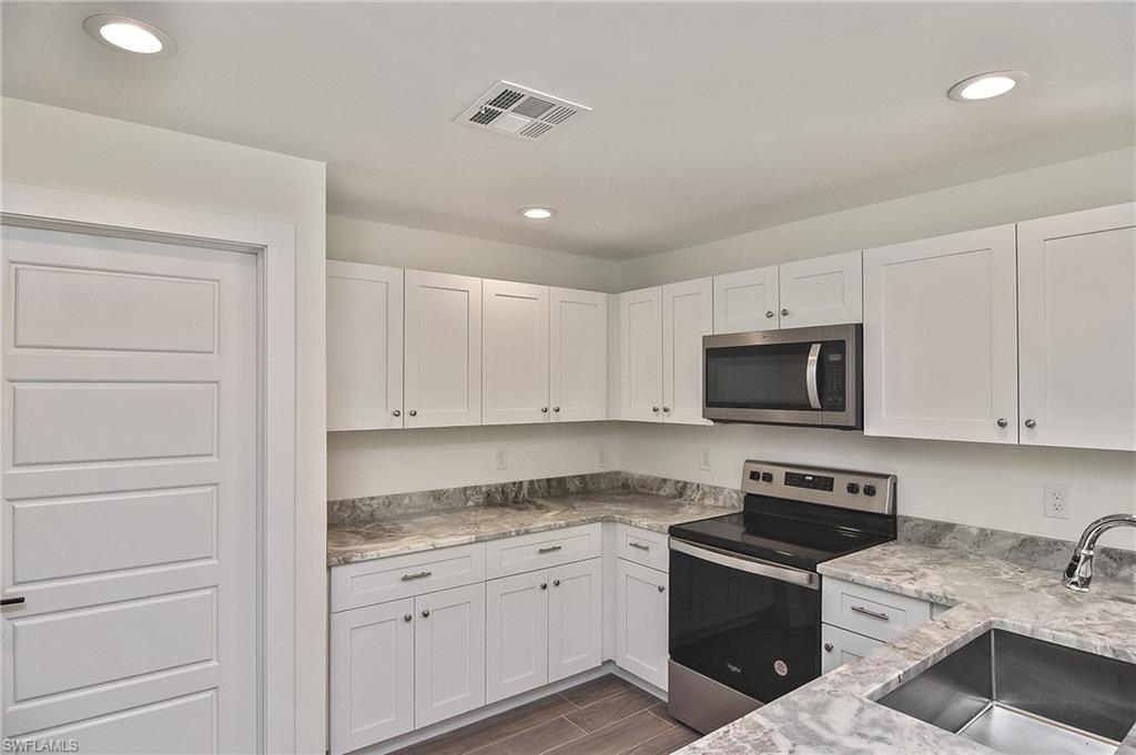 785 Homestead Road South Lehigh Acres, FL 33974 - Photo 24 of 49 a kitchen with granite countertop white cabinets and stainless steel appliances