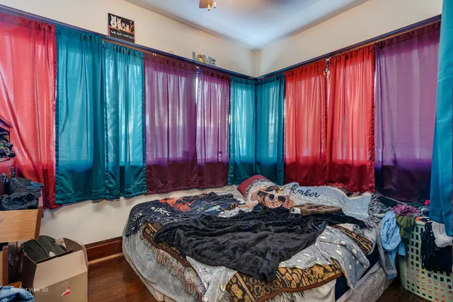 a bed sitting in a bedroom next to a window and a chair