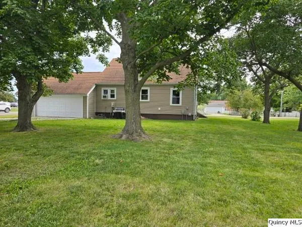 a house that is sitting in the grass with tress in the background