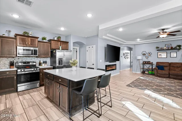 a kitchen with granite countertop a table chairs microwave and refrigerator