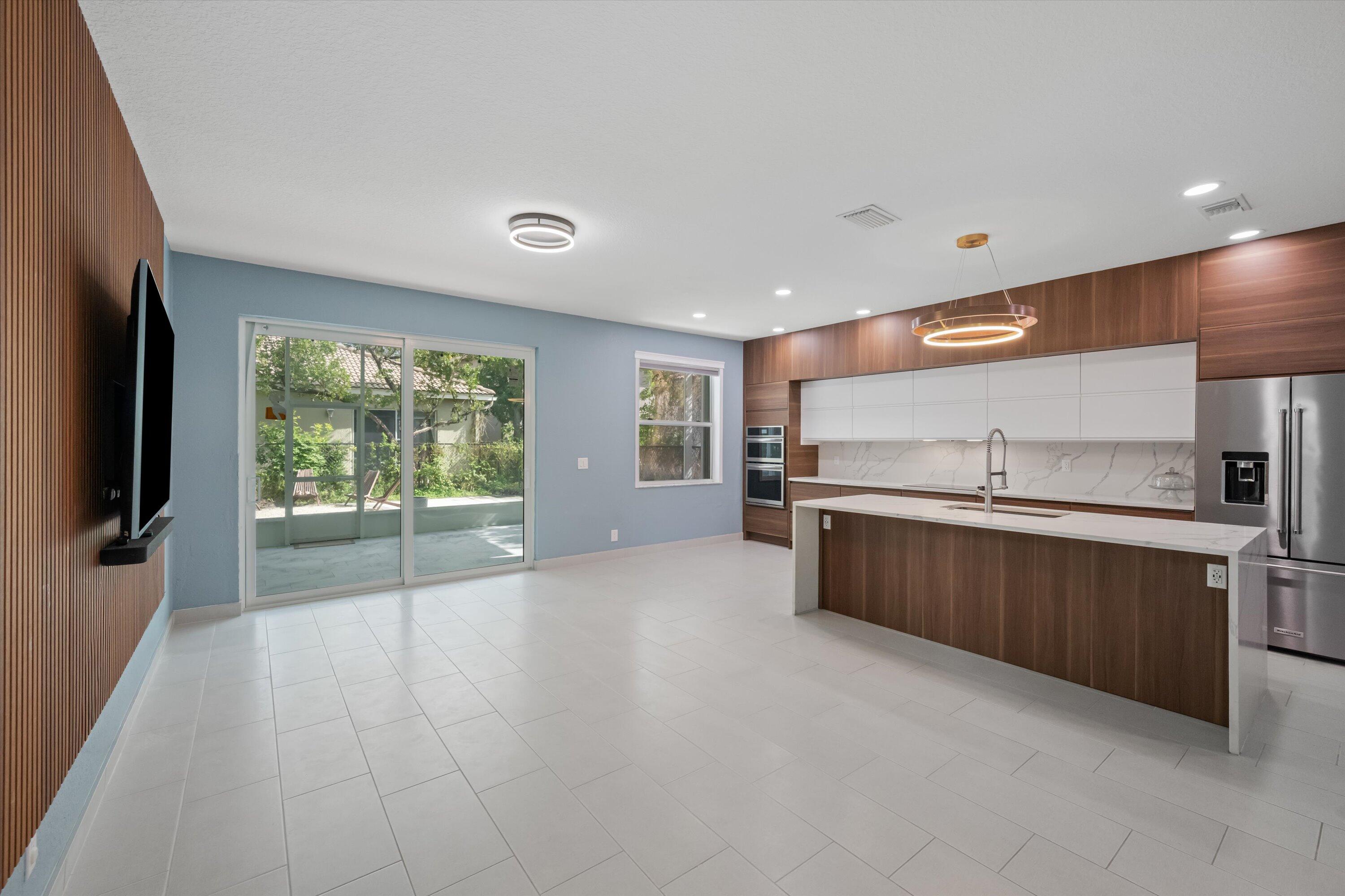 1222 Rose Gate Boulevard Riviera Beach, FL 33404 - Photo 2 of 29 a large kitchen with stainless steel appliances a large counter top a stove and a refrigerator