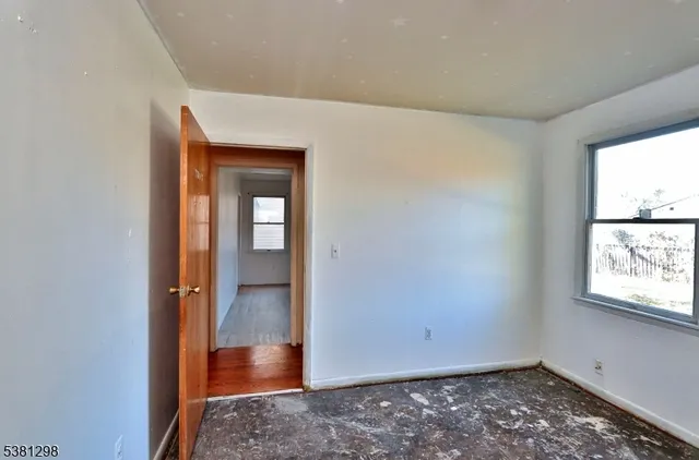 a view of an empty room with window and wooden floor