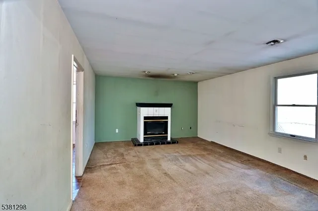 a view of an empty room with a window and fireplace