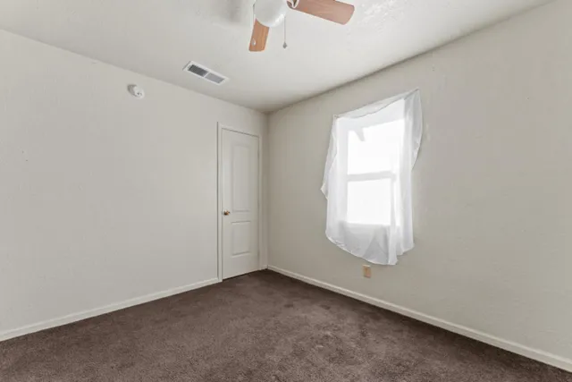 an empty room with a window and a ceiling fan