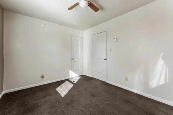 an empty room with ceiling fan and window