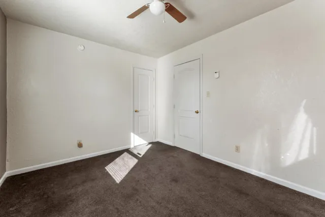 an empty room with ceiling fan and window