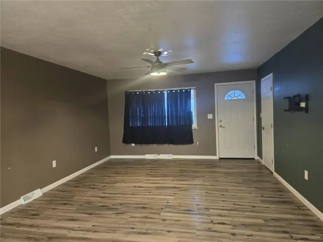 a view of an empty room with a ceiling fan and entryway