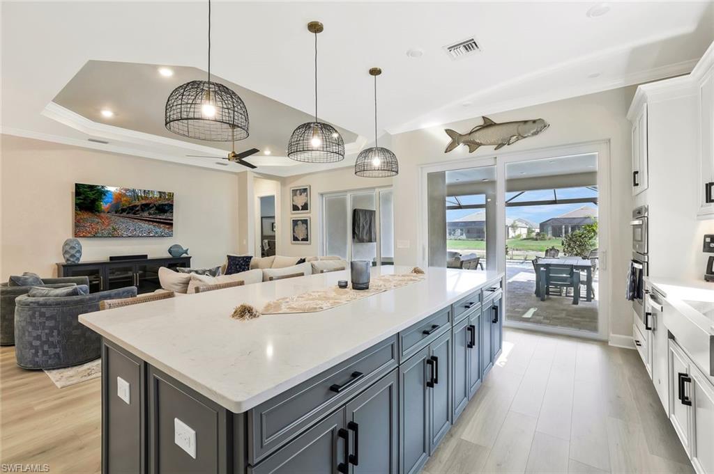 15804 Derna Street Naples, FL 34114 - Photo 28 of 28 Kitchen with white cabinets, pendant lighting, open floor plan, light stone countertops, and ornamental molding