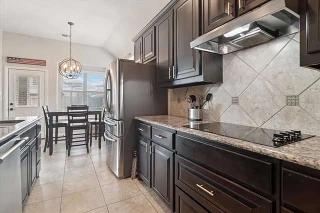 a kitchen with stainless steel appliances granite countertop a sink a stove and a wooden cabinets