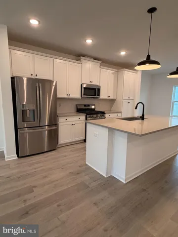 an empty room with wooden floor and kitchen view