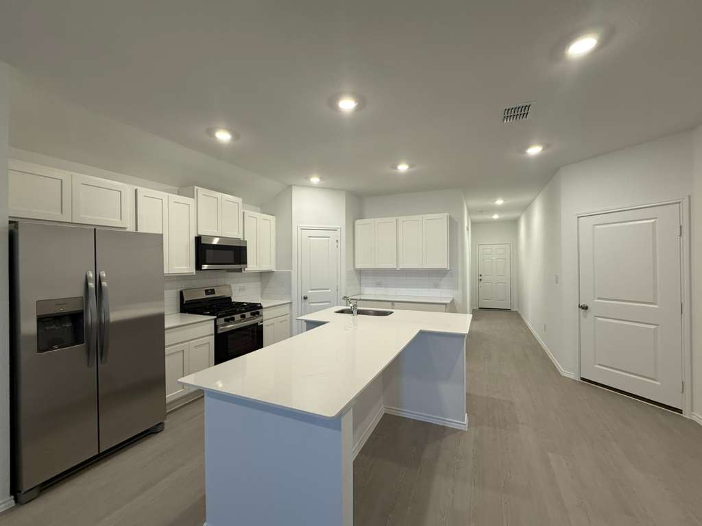 569 Sormonne Loop Kyle, TX 78640 - Photo 11 of 40 a kitchen with a refrigerator a stove top oven a sink and cabinets