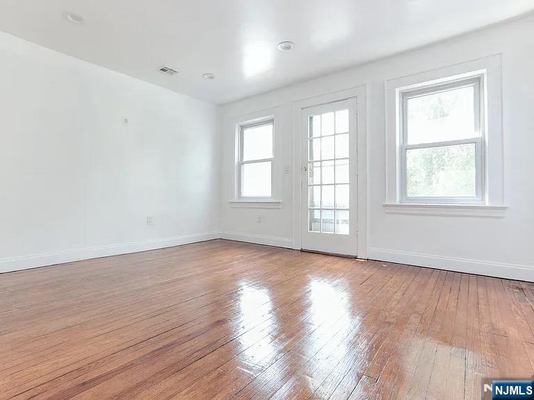 202 Kerrigan Boulevard Newark, NJ 07106 - Photo 2 of 5 an empty room with wooden floor and windows