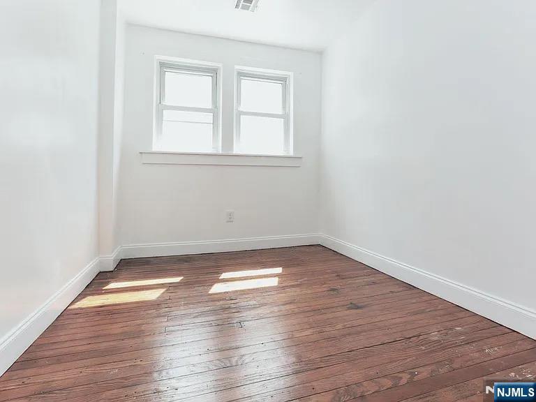 202 Kerrigan Boulevard Newark, NJ 07106 - Photo 4 of 5 an empty room with wooden floor and windows