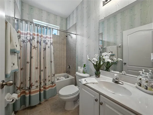 a bedroom with a bed potted plant on the dresser and a chandelier