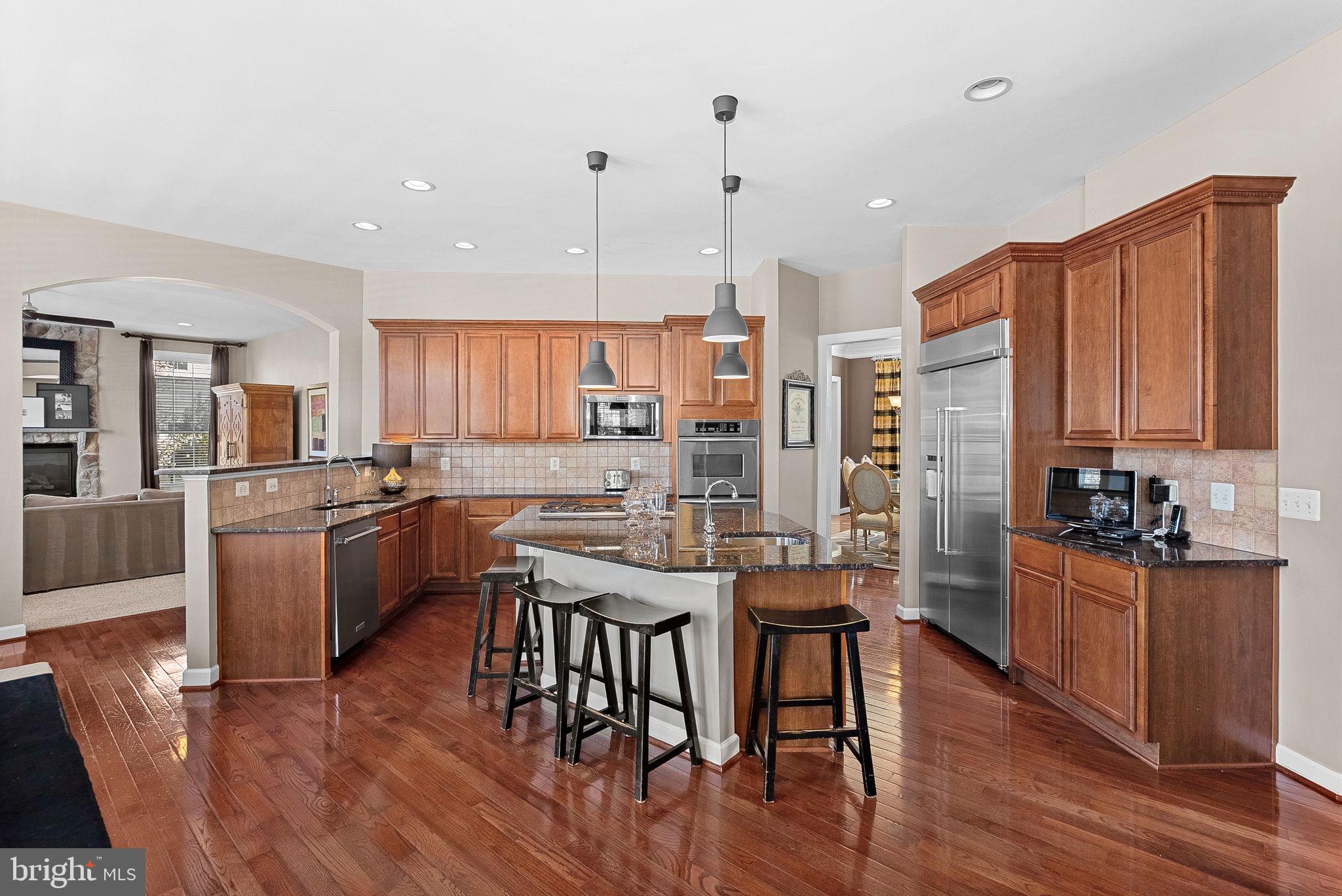22461 Terra Rosa Place Ashburn, VA 20148 - Photo 11 of 67 a kitchen with stainless steel appliances kitchen island granite countertop wooden floors and wooden cabinets