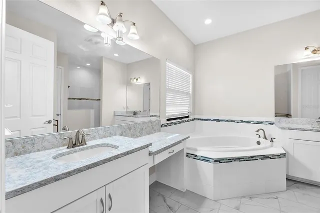 a bathroom with a granite countertop bathtub sink vanity and mirror