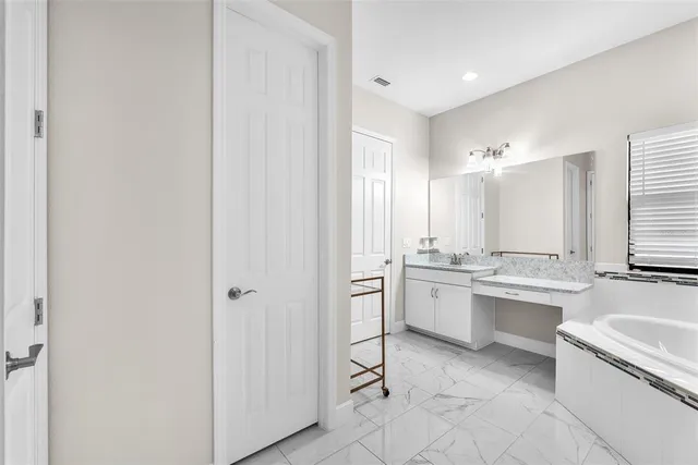 a large bathroom with a granite countertop double vanity sink a mirror and a bathtub