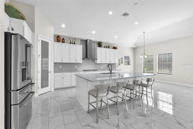 a kitchen with stainless steel appliances granite countertop a stove a sink a refrigerator and white cabinets with wooden floor