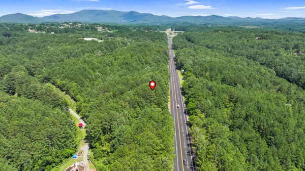 a view of a lush green forest with a house in a back