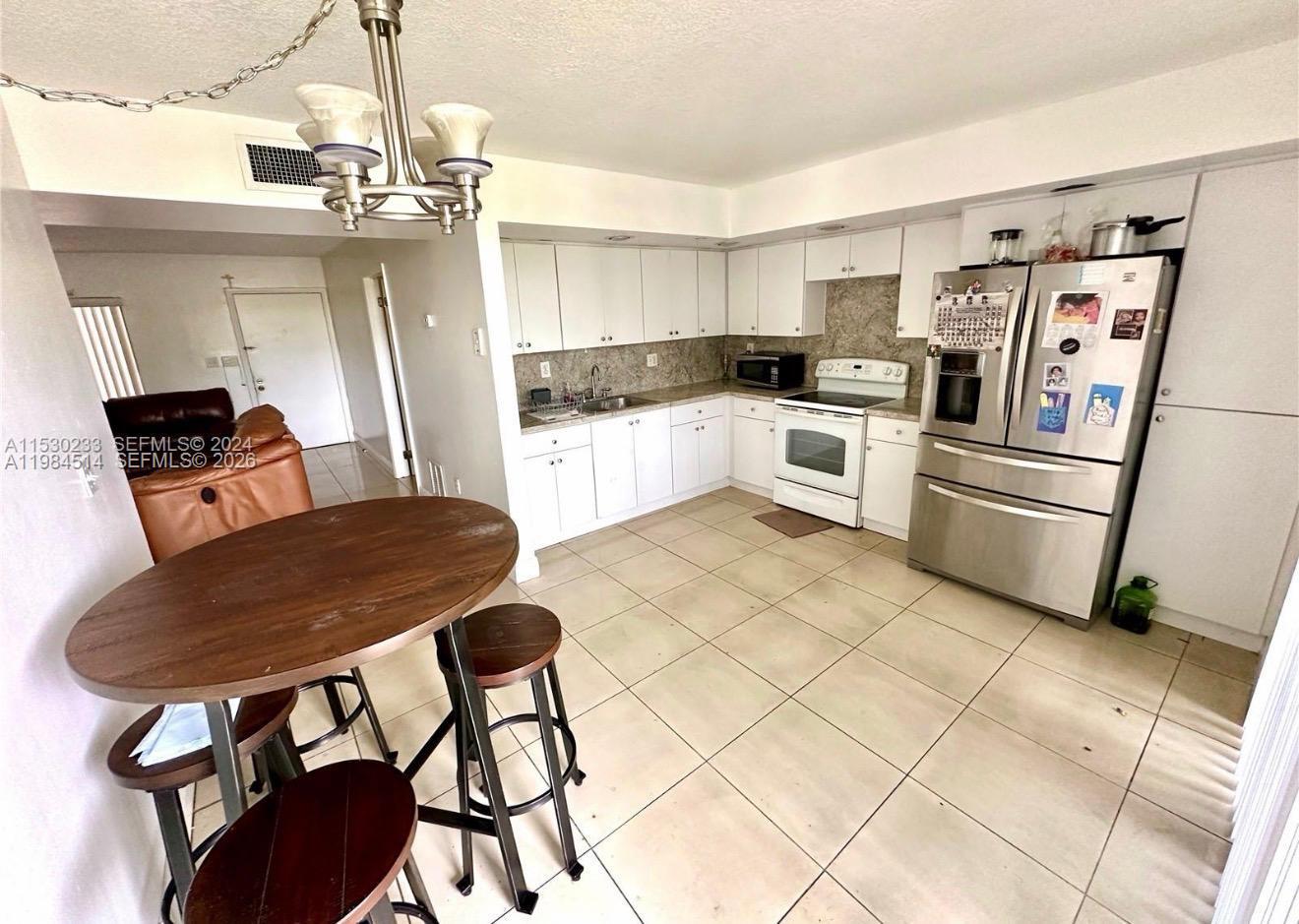 8650 Southwest 133rd Avenue Road, Unit 314 Miami, FL 33183 - Photo 1 of 13 a kitchen with stainless steel appliances kitchen island granite countertop a refrigerator a stove a sink dishwasher and white cabinets with wooden floor