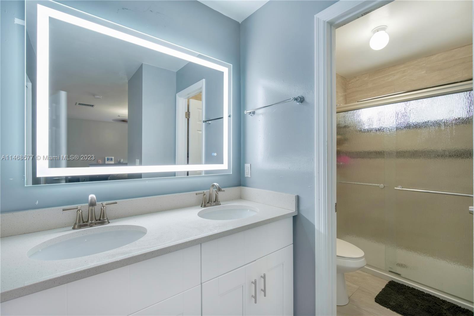 5232 Gate Lake Road, Unit 5232 Tamarac, FL 33319 - Photo 18 of 37 a bathroom with a granite countertop toilet a sink and a mirror