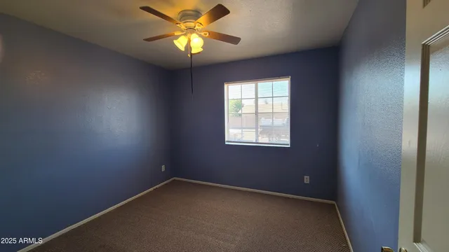 an empty room with a window and a fan