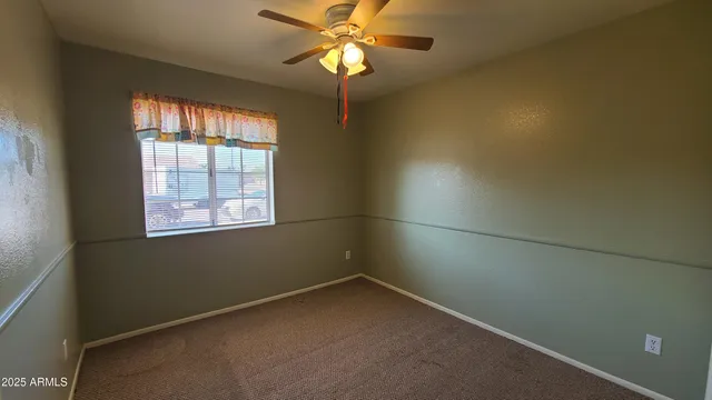 an empty room with a window and a fan