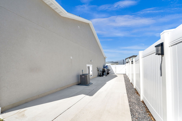 6120 North Sheps Ridge Road Eagle Mountain, UT 84005 - Photo 40 of 43 Concrete RV parking alongside of home, featuring a white vinyl fence and a gravel strip
