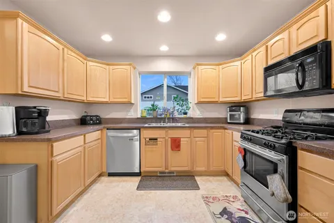 a kitchen with stainless steel appliances granite countertop a stove a sink and a microwave