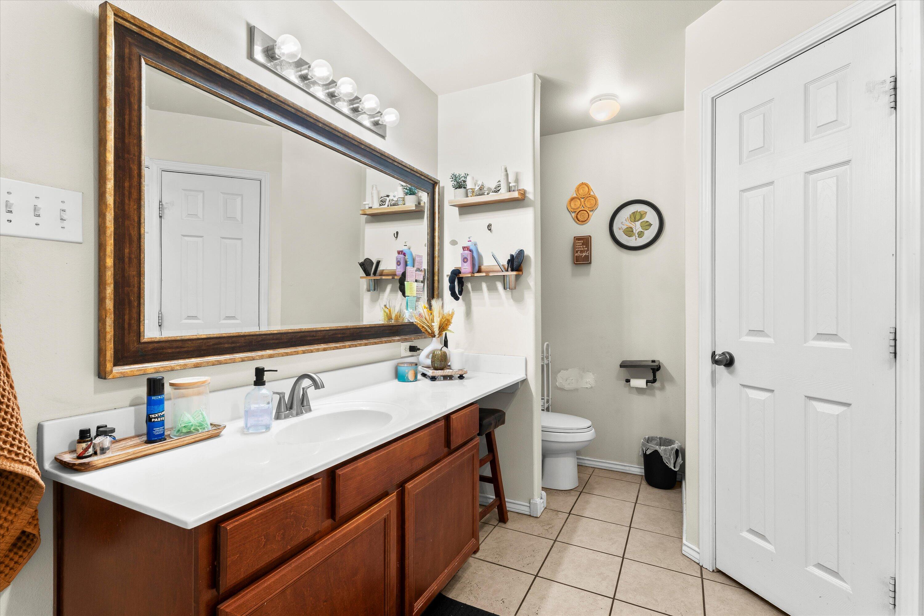 6513 85th Street Lubbock, TX 79424 - Photo 15 of 22 a bathroom with a sink a toilet a mirror and shower