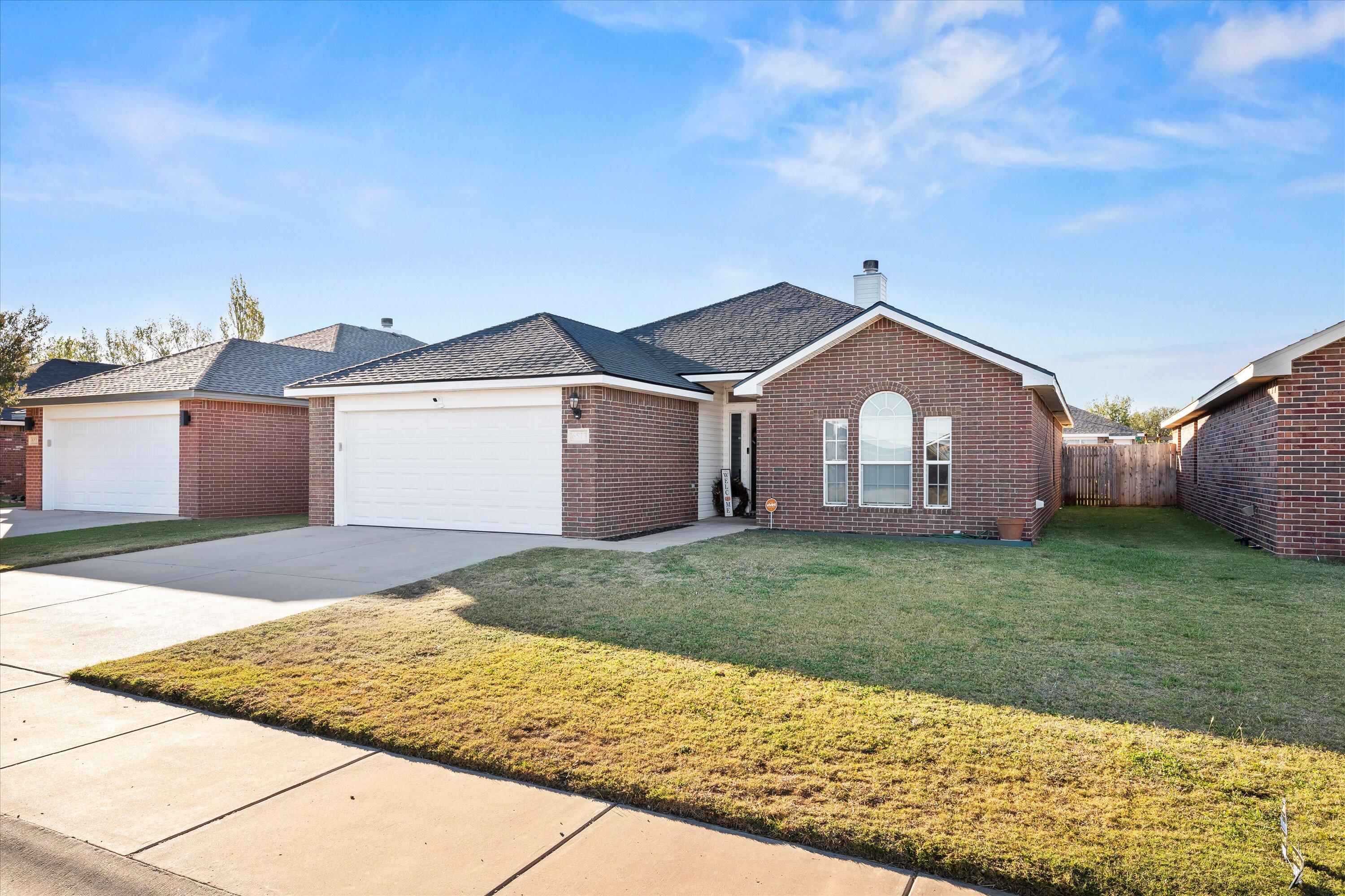 6513 85th Street Lubbock, TX 79424 - Photo 2 of 22 a front view of a house with a garden and yard