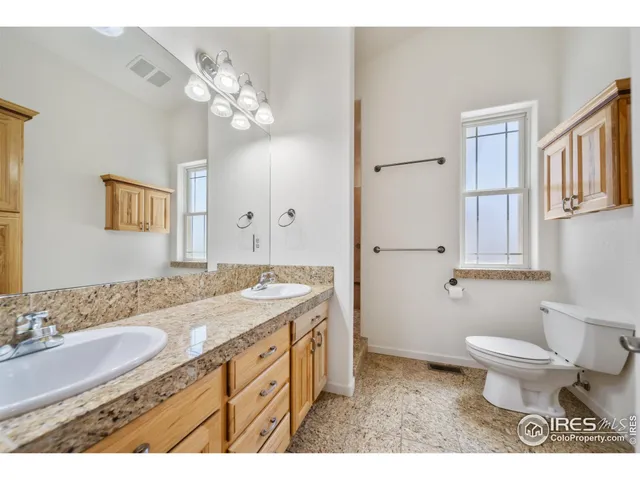 a bathroom with a granite countertop sink a toilet a mirror and shower