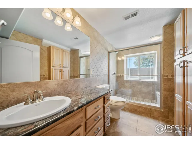 a bathroom with a granite countertop sink a mirror and a shower