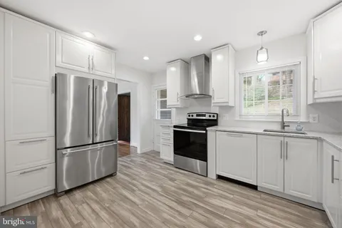 a kitchen with granite countertop stainless steel appliances a refrigerator cabinets and wooden floor