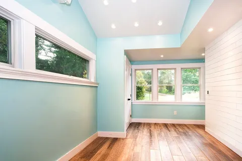 an empty room with wooden floor and windows