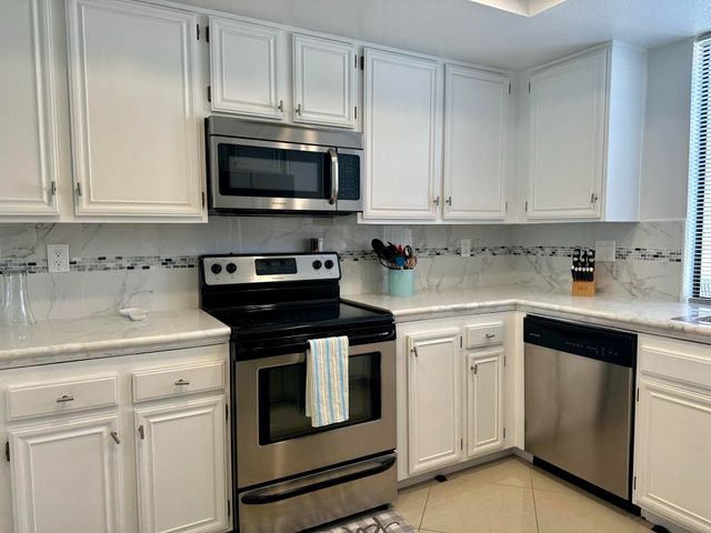 a kitchen with white cabinets and stainless steel appliances