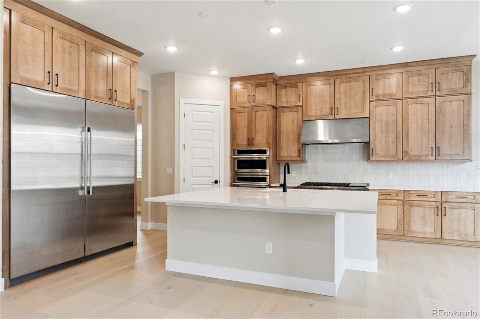 1288 Oleander Street Castle Rock, CO 80109 - Photo 5 of 29 a large kitchen with stainless steel appliances a refrigerator and a stove top oven