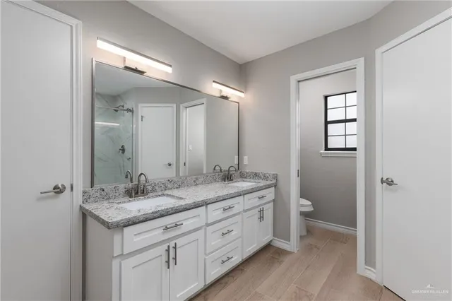 a bathroom with a granite countertop sink a toilet and a mirror