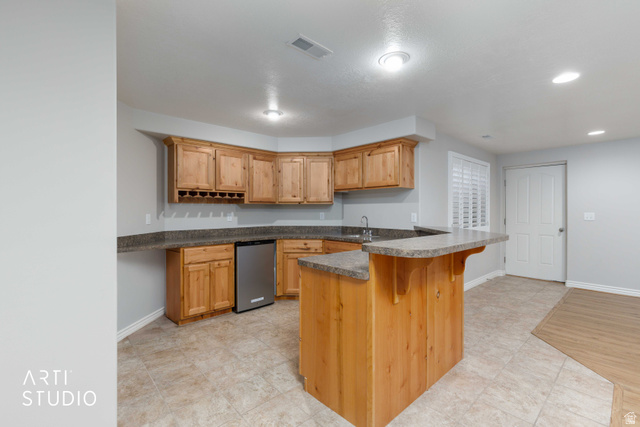 2327 Bluff Ridge Drive Syracuse, UT 84075 - Photo 28 of 66 Corner kitchen or wet bar featuring wood cabinetry, integrated wine rack, and a stainless steel under-counter refrigerator