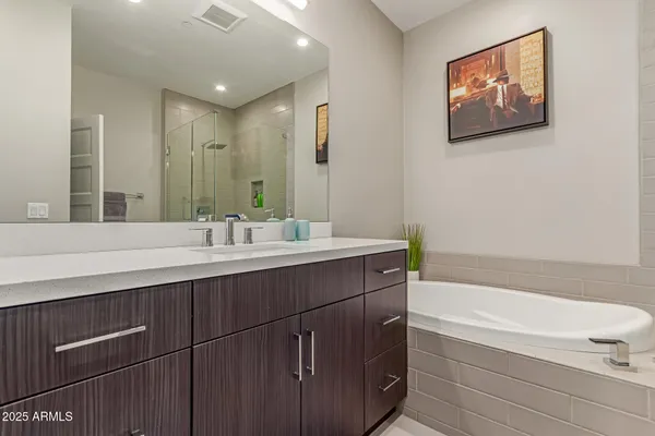 a bathroom with a double vanity sink a large mirror a bathtub and a shower