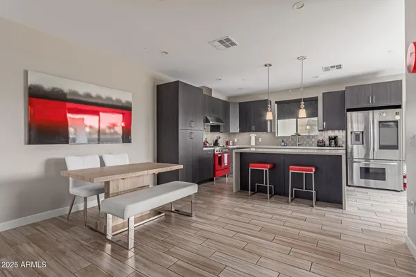 a living room with stainless steel appliances kitchen island granite countertop a dining table chairs and a refrigerator