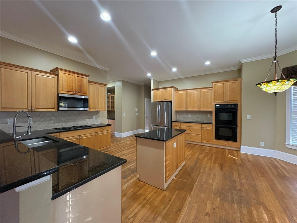 5930 Abbotts Run Trail Duluth, GA 30097 - Photo 5 of 32 a view of a kitchen with kitchen island a sink wooden floor and a counter top space