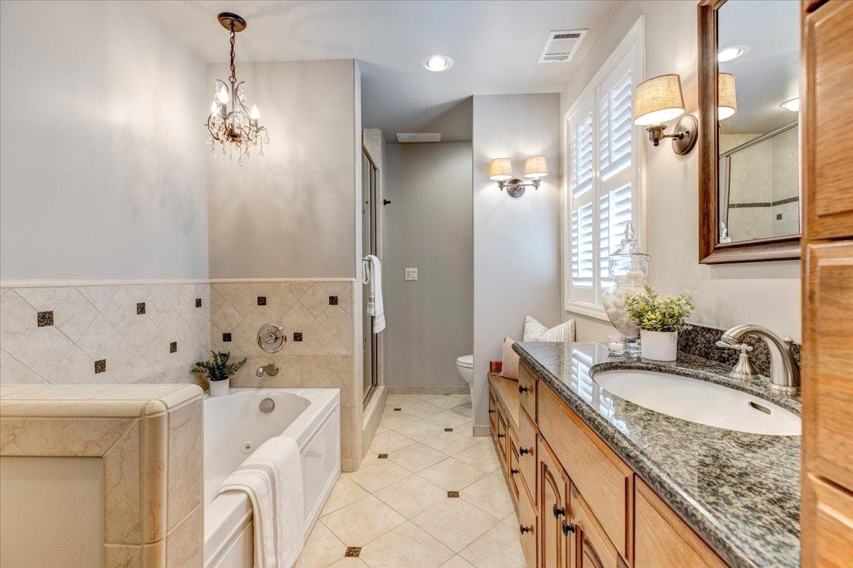 6763 Endmoor Drive San Jose, CA 95119 - Photo 19 of 32 a bathroom with a granite countertop sink a mirror a vanity and shower