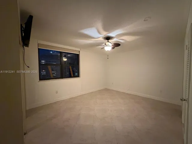 a view of an empty room with chandelier fan