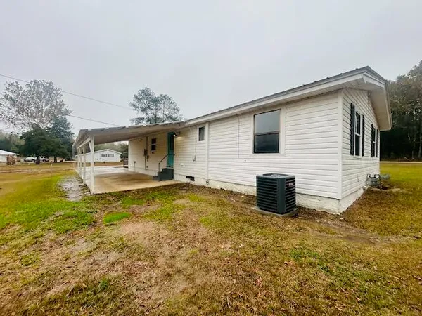 a view of house with backyard and trees in the background