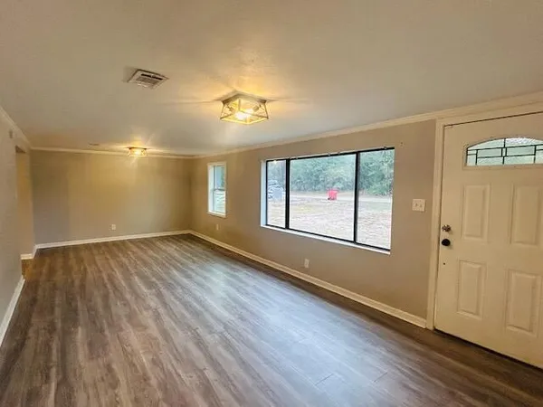an empty room with wooden floor and windows