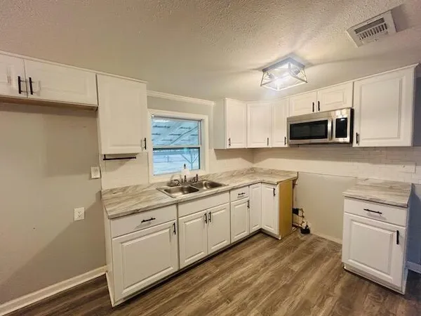 a kitchen with granite countertop white cabinets and white appliances